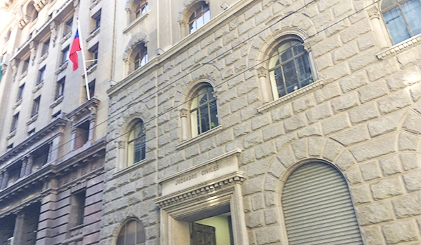 Imagem de um edifício antigo com detalhes arquitetônicos clássicos na fachada, localizado em uma área urbana de cidade grande, com janelas de arco.