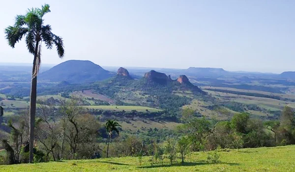 Paisagem natural na região de Brasília com morros, árvores e uma vasta área verde sob céu claro. Viagem à Botucatu e Barra Bonita.