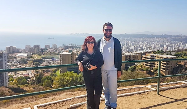 Deusa Rodrigues e Rafael aproveitando vista panorâmica na cidade de fronte mar com horizonte ao fundo, em passeio ao ar livre de dia ensolarado.