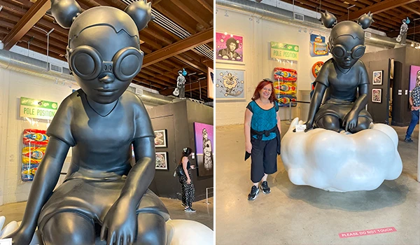 Escultura de uma menina com óculos grandes em preto, instalada em uma galeria de arte, com visitantes ao redor e obras no fundo. O que fazer em Wynwood, Miami.