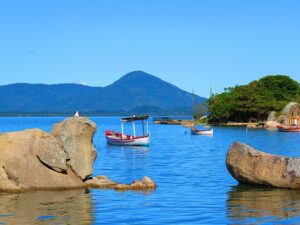 Vista do mar entre montanhas e pedras com barcos em Florianópolis