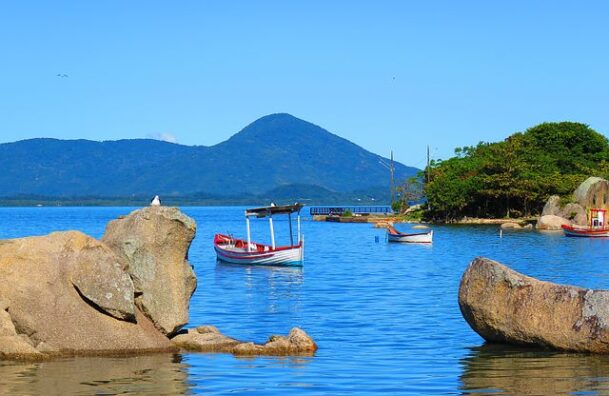 Vista do mar entre montanhas e pedras com barcos em Florianópolis