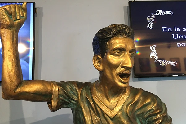 Estátua de bronze de um jogador de futebol, com braço levantado em comemoração no Museu do Futebol em Montevideu.