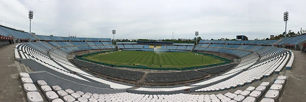 Estádio de futebol vazio, estrutura moderna e arquibancadas ao redor do campo, pronto para uma partida de futebol.