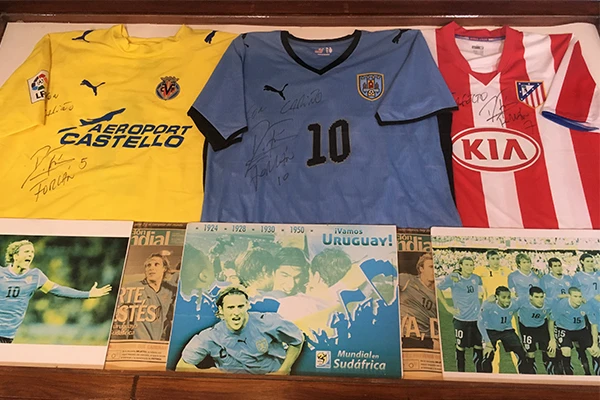 Coleção de camisas de times de futebol, incluindo a camisa adidas azul da seleção uruguaia com o número 10 entre outras, uma das dicas sobre o que fazer em Montevidéu.