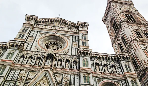 Detalhe da fachada da Catedral de Santa Maria del Fiore, em Florença, com a ornamentação em mármore, a grande rosácea e o campanário ao lado. Lua de Mel na Itália.