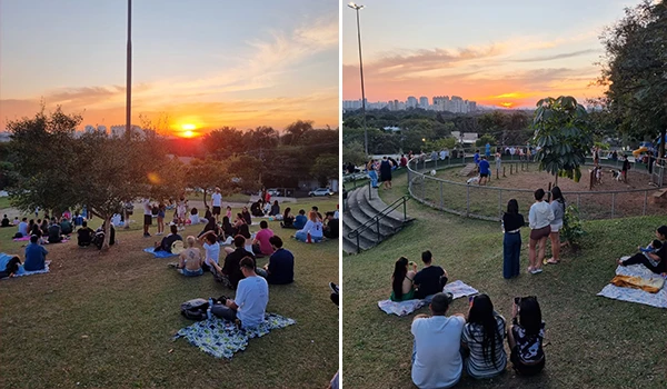 Pessoas apreciando o pôr do sol em um parque ao ar livre com céu colorido ao entardecer, famílias sentadas em mantas e grupos de amigos curtindo a natureza.