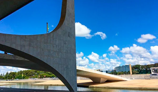 Imagem da arquitetura moderna de Oscar Niemeyer com estrutura de concreto e céu com nuvens, destaque para design inovador e paisagem urbana. Lua de Mel em Brasília.