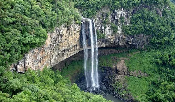 Cachoeira exuberante cercada por vegetação verde densa e falésias rochosas em uma paisagem natural, ideal para quem busca tranquilidade e contato com a natureza.