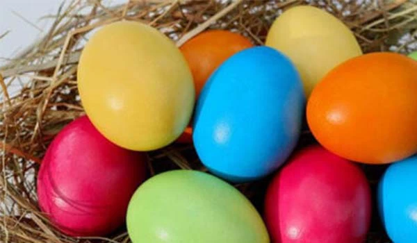 Ovos de páscoa coloridos em um ninho de palha, prontos para comemoração de Páscoa, com cores vibrantes como amarelo, azul, verde, rosa e laranja.