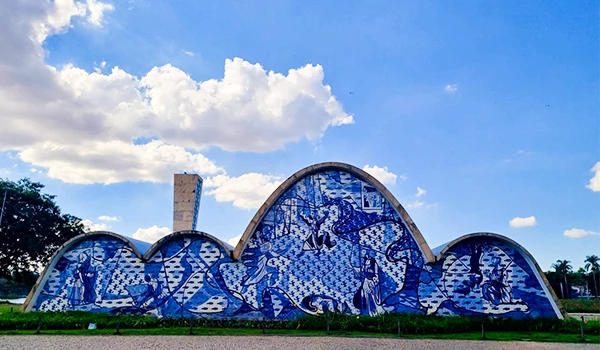 Foto de mural em azul com múltiplas formas onduladas e personagens representando a cultura local.