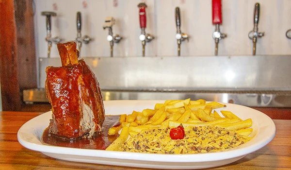 Deliciosa costela suculenta com batatas fritas e acompanhamento de purê de carne. Um dos pratos de restaurante de Poços de Caldas.