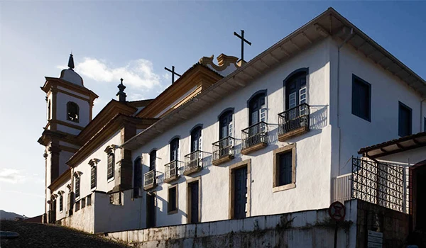 Igreja histórica com detalhes arquitetônicos, janelas em destaque e cruzes no topo, representando o patrimônio cultural, em Mariana.