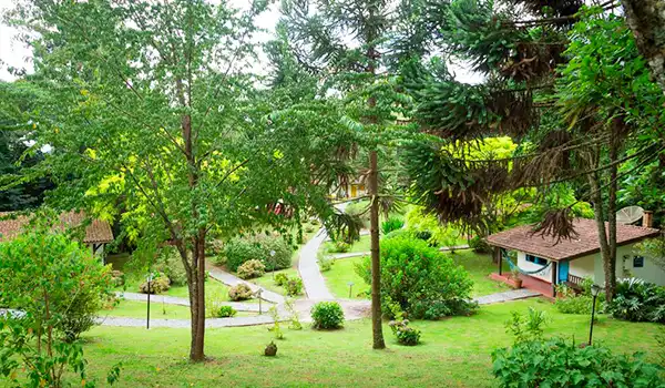 Vista panorâmica de um belo jardim com árvores verdejantes, caminhos na pousada Trem da Cores em Gonçalves, ideal para Lua de Mel em Minas Gerais.