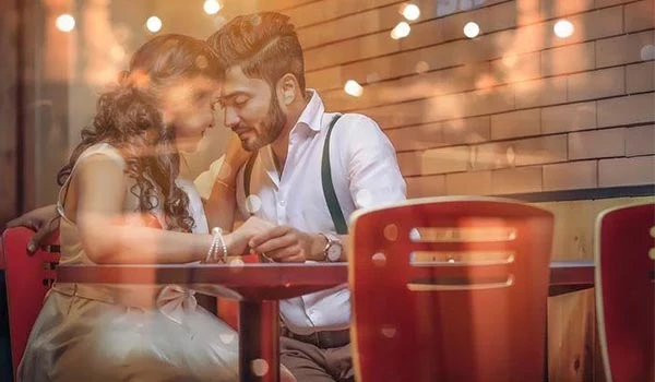 Casal apaixonado em um ambiente romântico, compartilhando um momento especial em um restaurante com iluminação suave e decoração aconchegante. Ideal para Lugares para comemorar aniversário de casamento.