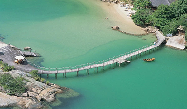 Ponte de madeira sobre águas cristalinas em uma praia tranquila, ideal para relaxar e aproveitar a natureza. Lugares para comemorar aniversário de casamento.
