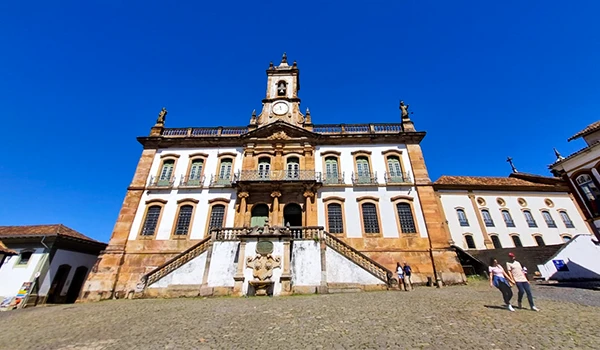 Vista da Praça dos Martires em Ouro Preto, destacando a arquitetura colonial do século XVIII e o céu azul ao fundo, cenário perfeito para Lua de Mel em MInas Gerais.