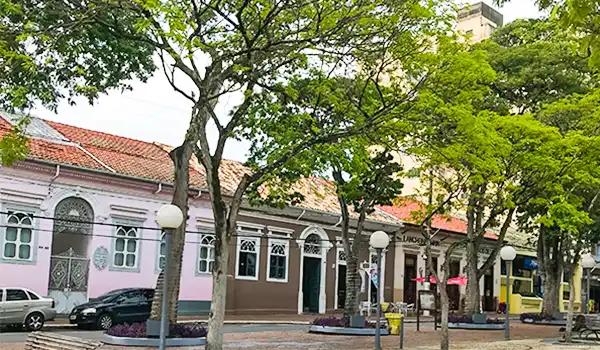 Vista da arquitetura colonial em uma rua arborizada, com casas coloridas e uma atmosfera tranquila, ideal para passeios e turismo.