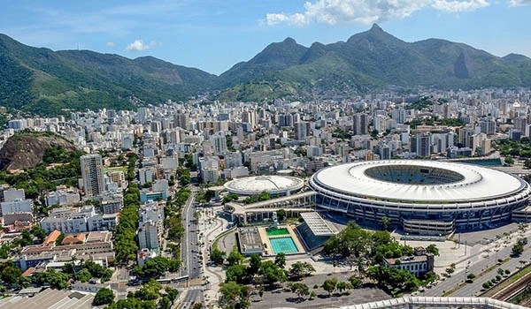 Vista aérea do estádio icônico localizado no Rio de Janeiro, com cidade e montanhas ao fundo, em um dia ensolarado na visita ao Maracanã.