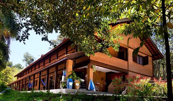 Foto do Hotel Campo dos Sonhos, uma construção grande com tijolos a vista com arquitetura bonita e várias redes nas varandas.
