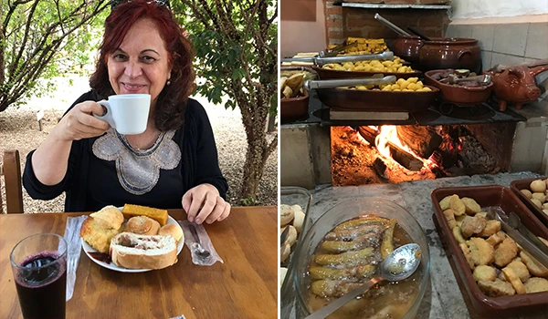 Deusa Rodrigues com um copo de café à mesa, rodeada por pratos de comida em um ambiente rústico e aconchegante. A imagem mostra a deliciosa culinária caseira.