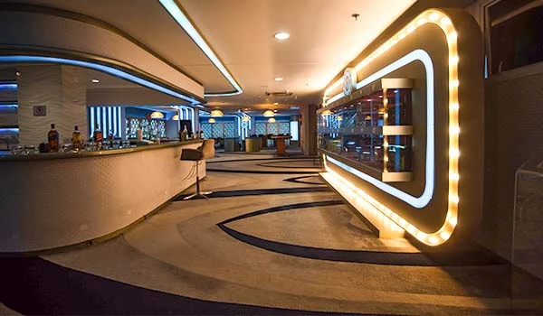 Interior de bar moderno com iluminação elegante, mesas e um ambiente sofisticado. Dicas da Lua de Mel no Jequitimar Guarujá.