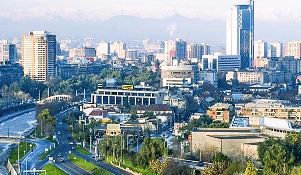 Vista panorâmica da cidade de Santiago mostrando arranha-céus modernos, ruas movimentadas e montanhas ao fundo em um dia claro. Travessia dos Lagos Andinos.