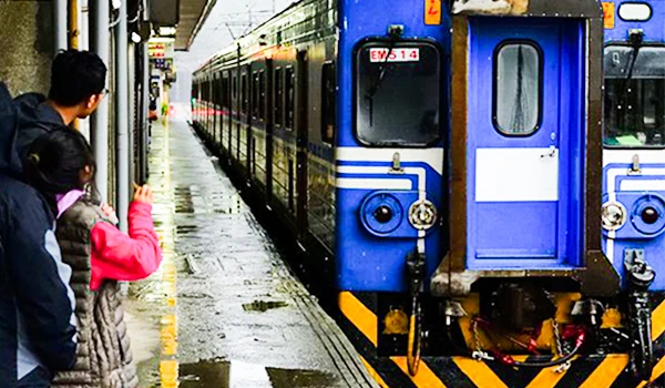 Foto de um trem azul chegando e passeiros a espera na plataforma.