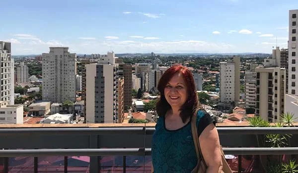 Foto de Deusa Rodrigues em um mirante de hotel com vista de Campinas.