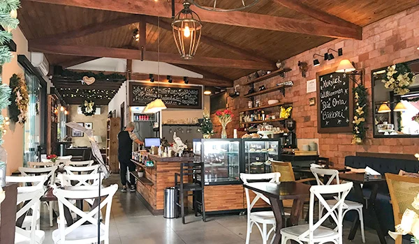 Foto de um restaurante de Campinas onde se observa mesas, cadeiras, balcão com produtos e funcionários.