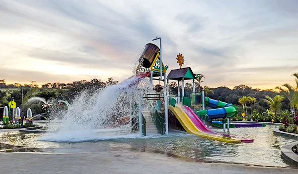 Foto uma área de piscina com escorregadores e balde com água que se transforma em cachoeira.
