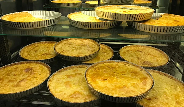 Foto de diversas tortas salgadas em vitrine de lanchonete em Campinas.