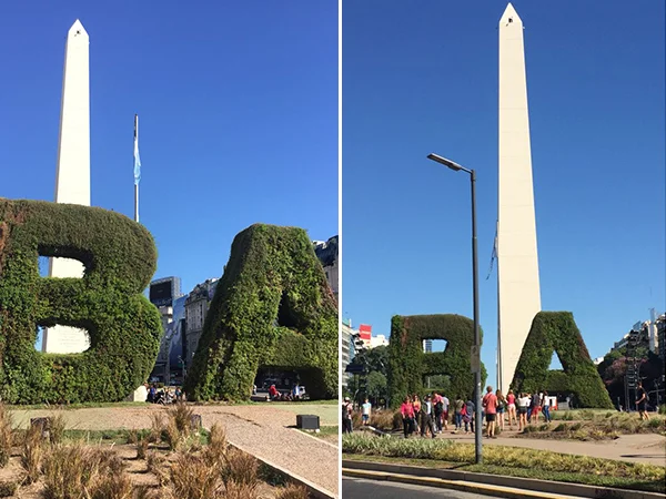 Obelisco de Buenos Aires, na Argentina, ao fundo de letras gigantes formadas por vegetação, com turistas ao redor em um dia ensolarado.