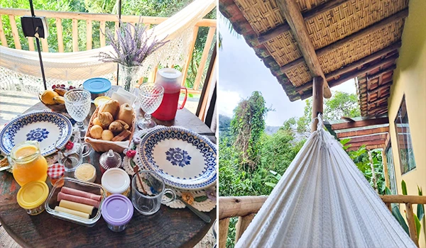 Café da manhã em uma varanda com pratos decorativos, pães, geleias, e uma rede de descanso, cercada por natureza em um ambiente acolhedor e relaxante.