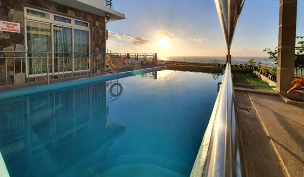 Foto do hotel Villa Paradise nas Ilhas Rodrigues com piscina e mar ao fundo em dia de sol.