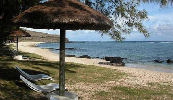 Foto de uma praia com várias barracas de palha, cadeiras em meio a vegetação nas Ilhas Rodrigues.