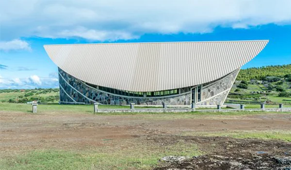 Foto de um prédio em estilo moderno com telhado arredondado em um campo com céu azul na Ilha Rodrigues.