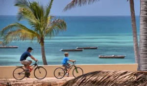 Bonita foto de um pai com filho andando de bicicleta na praia das Ilhas Mauritius.