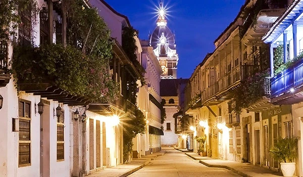Imagem de uma rua e histórica, com iluminação aconchegante e arquitetura colonial ao entardecer, destacando a beleza da cidade. Lua de Mel na Colômbia.