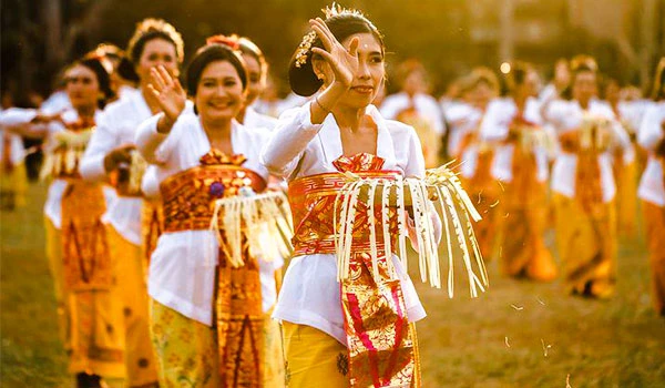 Grupo de mulheres em roupas tradicionais tailandesas participando de uma cerimônia cultural ao ar livre, com sorrisos e gestos de saudação. Casamento em Bali.