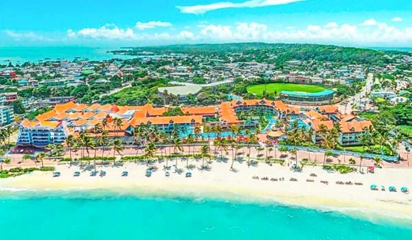 Imagem aérea de resort de praia com vista para o oceano, oferecendo praias de areia branca, piscina, estrutura de lazer e áreas verdes, ideal para férias e turismo.