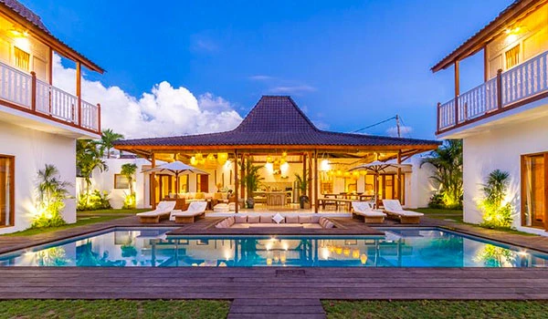 Imagem de um hotel com piscina, cercada por jardins bem cuidados, no pôr do sol, ideal para férias ou para o Casamento em Bali.