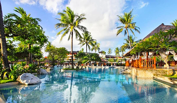 Piscina de resort tropical com espreguiçadeiras, palmeiras e ambiente relaxante em um cenário paradisíaco.
