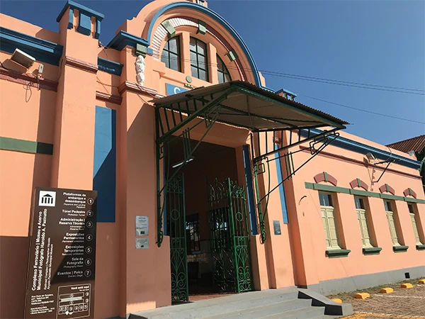 Vista do prédio antigo da Estação Ferroviária, cor rosa com detalhes em azul e verde, que está aberta à visitação uma das dicas sobre o que fazer em Valinhos.