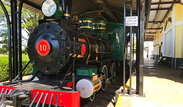 Imagem de uma locomotiva clássica em exposição, destacando seu design vintage e detalhes em vermelho e verde, parte do patrimônio histórico ferroviário.