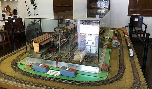 Modelo de uma ferrovia em miniatura exibido em um museu, com detalhes como estação e trilhos, perfeito para conhecer a história dos trens.