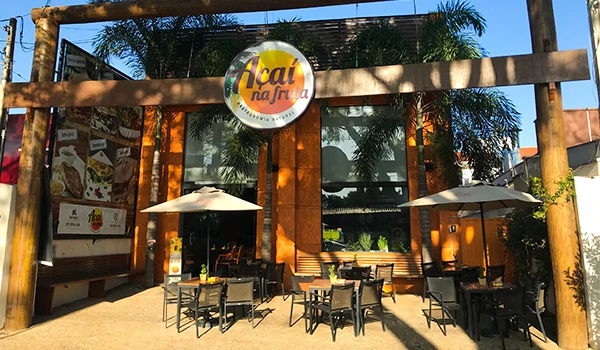 Vista externa do restaurante Açaí na Fruta, com mesas ao ar livre e decoração natural, ideal para desfrutar açaí fresquinho.
