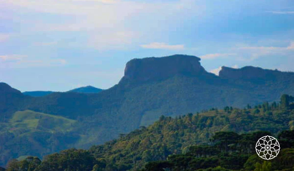 Paisagem de uma cadeia de montanhas verdes sob céu parcialmente nublado na região de Chapadão do Sul, destacando a beleza natural do cerrado brasileiro.