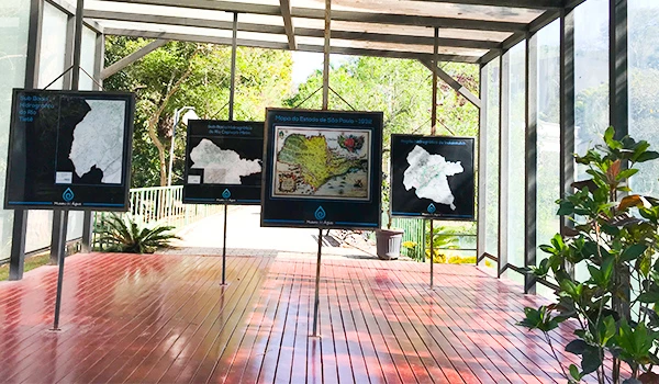 Imagem de um espaço expositivo com mapas pendurados, mostrando diferentes regiões e informações geográficas, ideal para estudos e pesquisas geográficas.