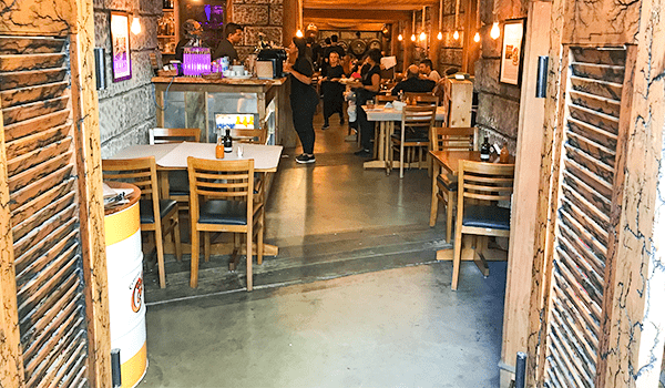 Foto da entrada do Mirandês, onde se observa as mesas, cadeiras, e clientes, o lugar tem estilo de uma taberna portuguesa, é um dos Bares da Santa Cecília.